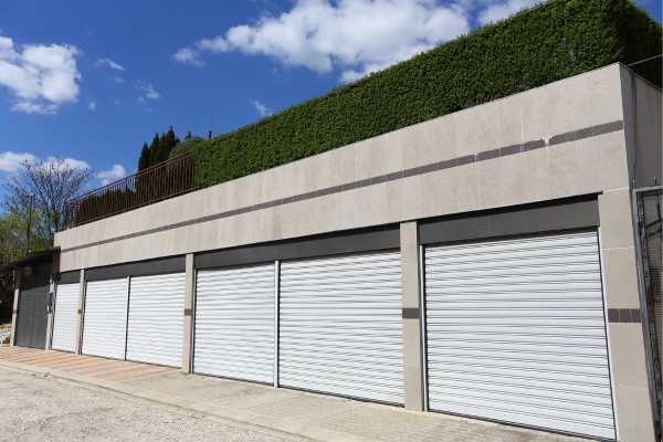 Commercial overhead garage doors fitted in a modern building with landscaped rooftop and clear blue skies
