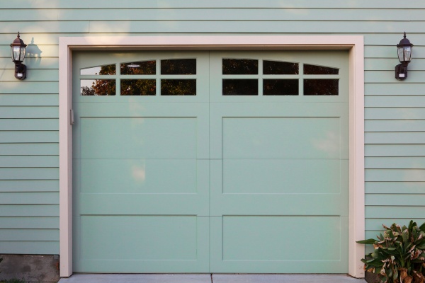 Garage door repair process taking place on a sunny day in a suburban neighborhood Garage door repair process