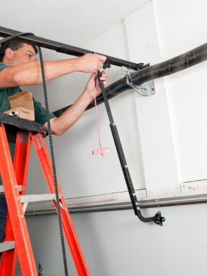 Garage door tune up service being performed by a technician near a residential location in the evening