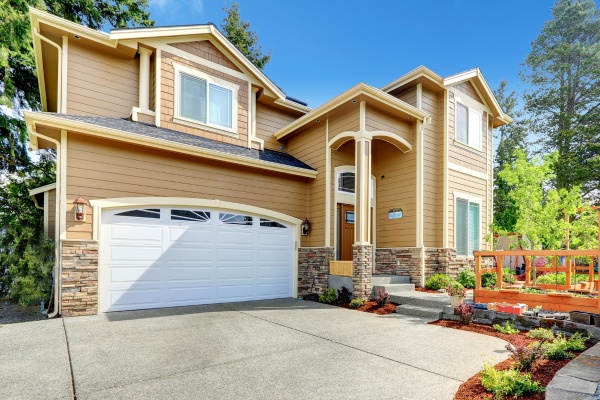 Overhead garage door in Stony Plain highlights a modern home with elegant landscaping and a welcoming entrance